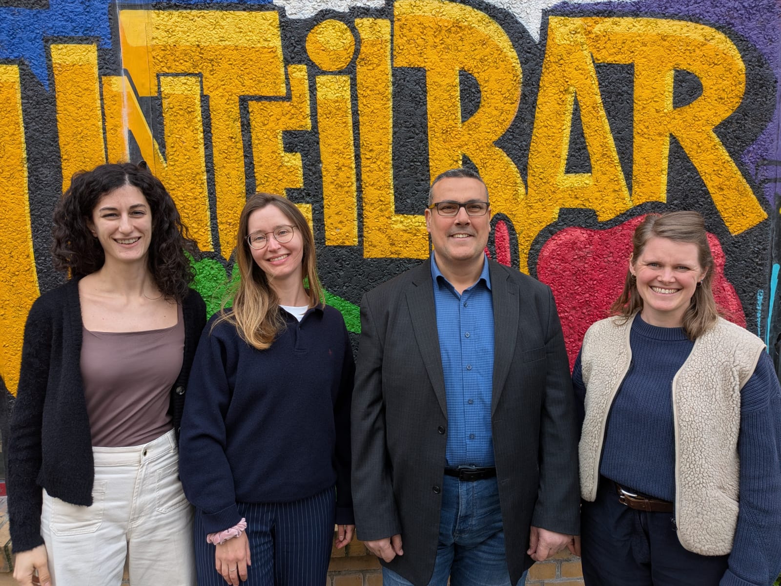 Vier Mitarbeiter:innen vor der Tür des WELCOME-Treffs